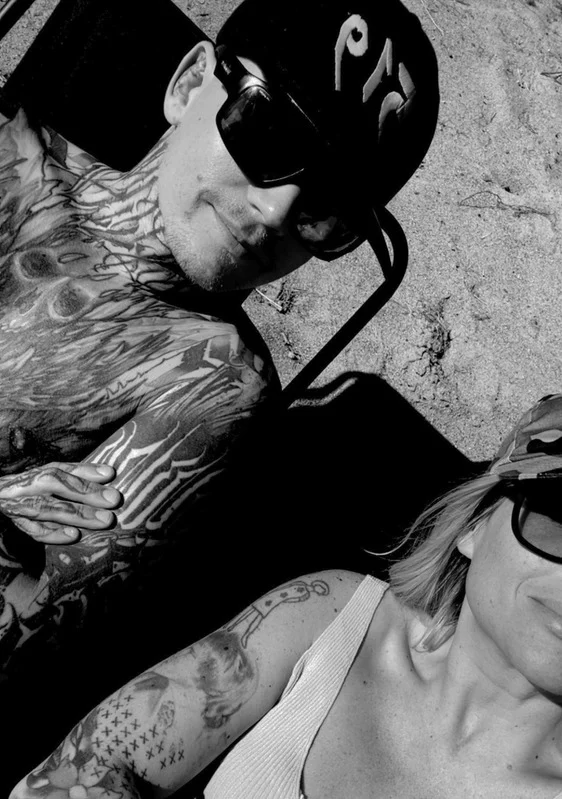 Annika och Marcus i solen, med solglasögon och synliga tatueringar
